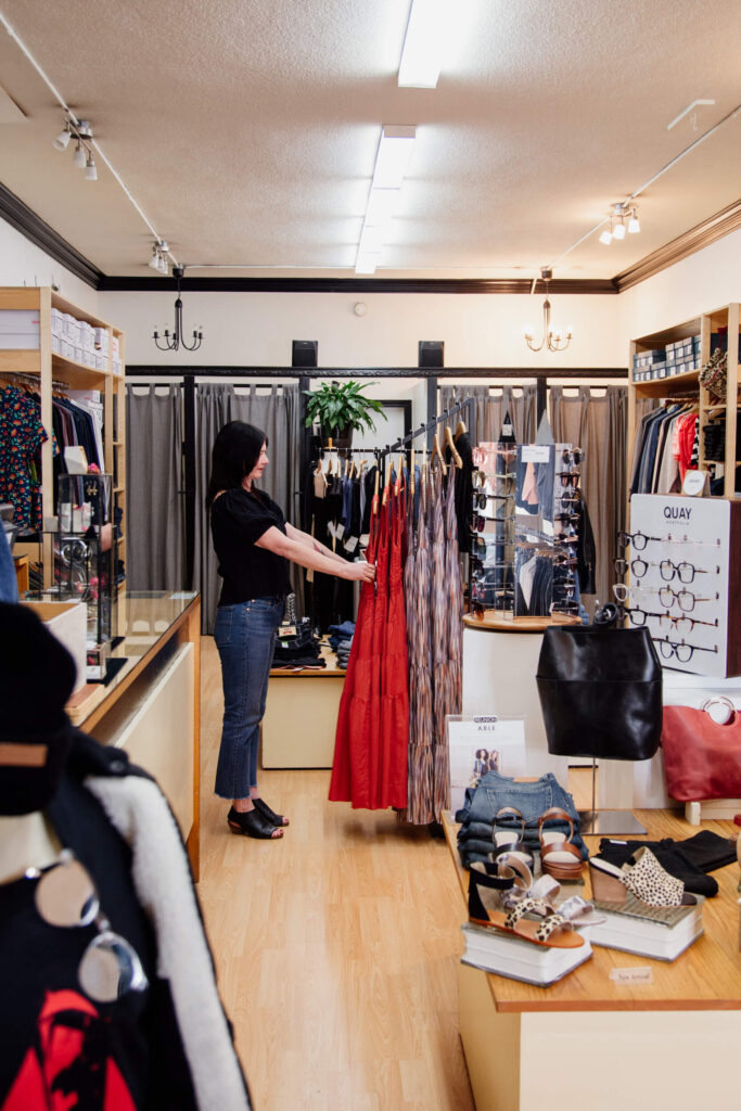 A shop owner fixing a dress on a rack in her store in Victoria, BC.