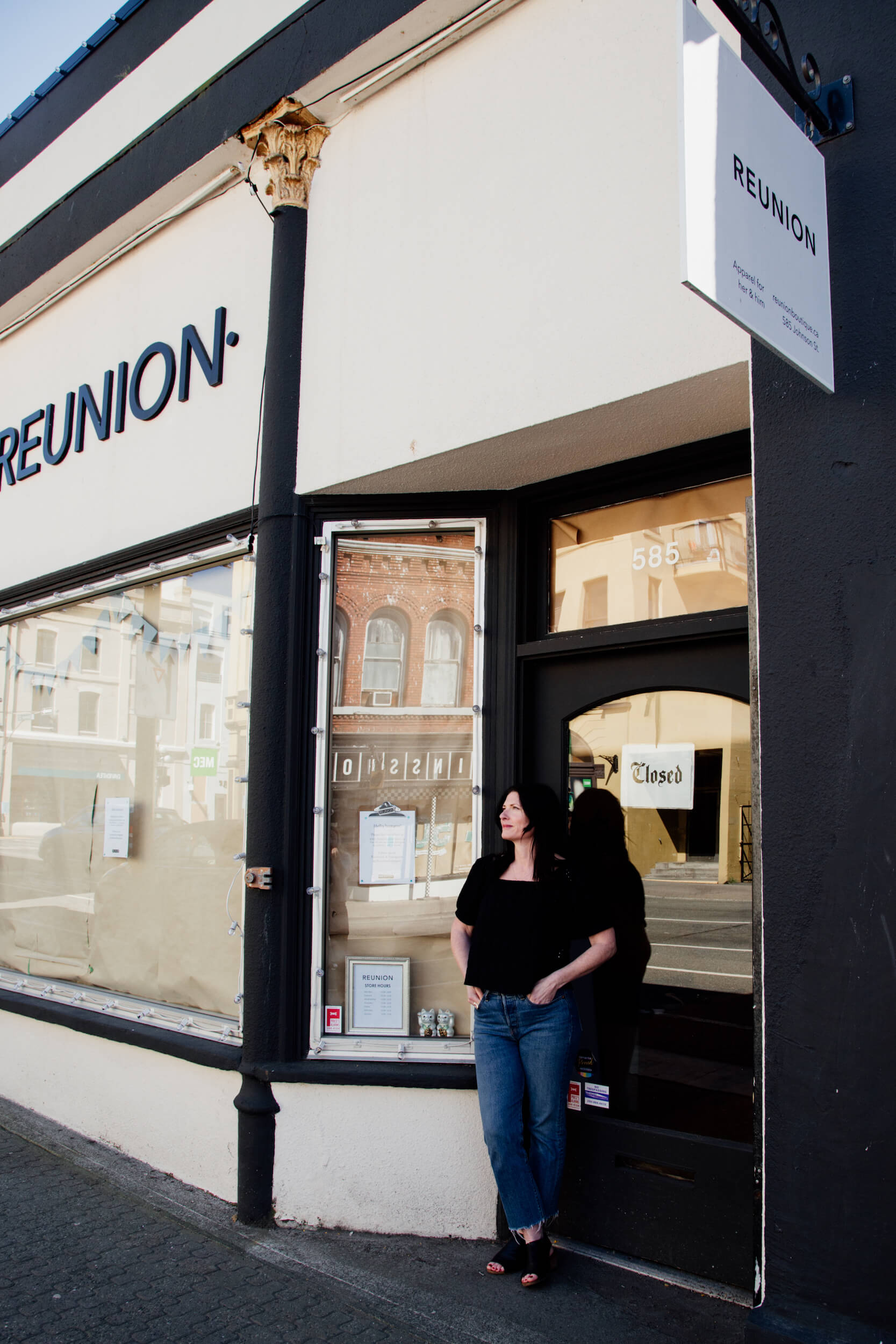 Shop owner stands in front of the papered windows of her store in Victoria, BC.