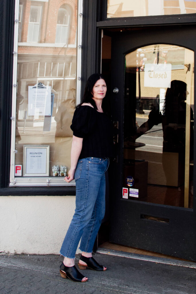 A shopkeeper standing outside her store in Victoria, BC.