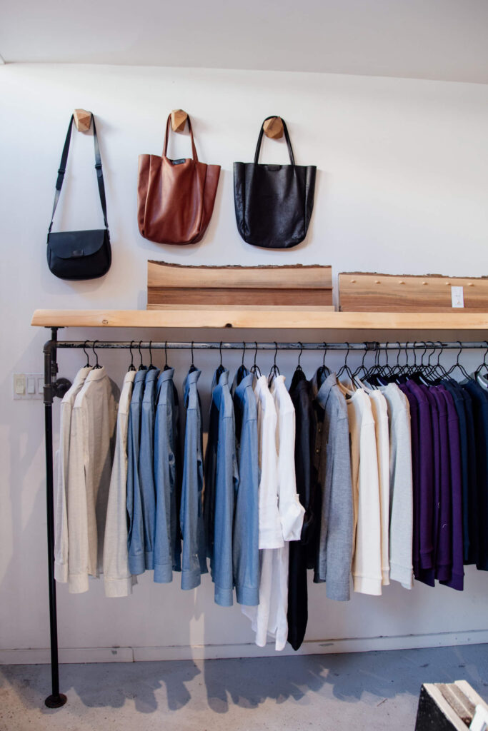 Clothes and bags hanging on a rack in a clothing shop in Victoria, Canada.