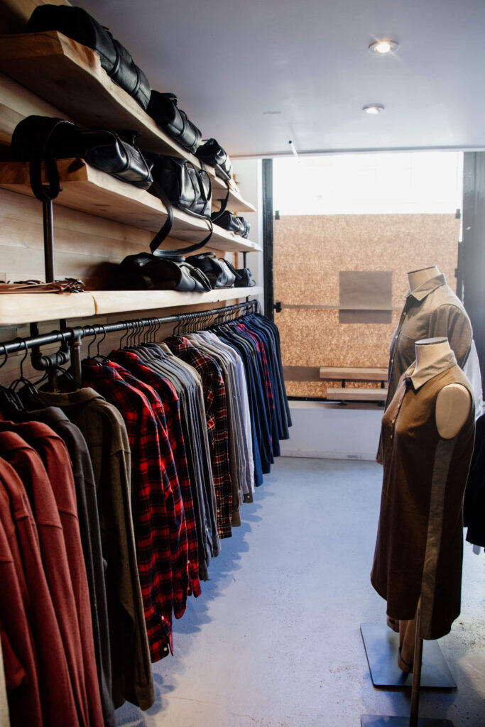 Clothes and bags hanging on a rack in a clothing shop in Victoria, Canada.