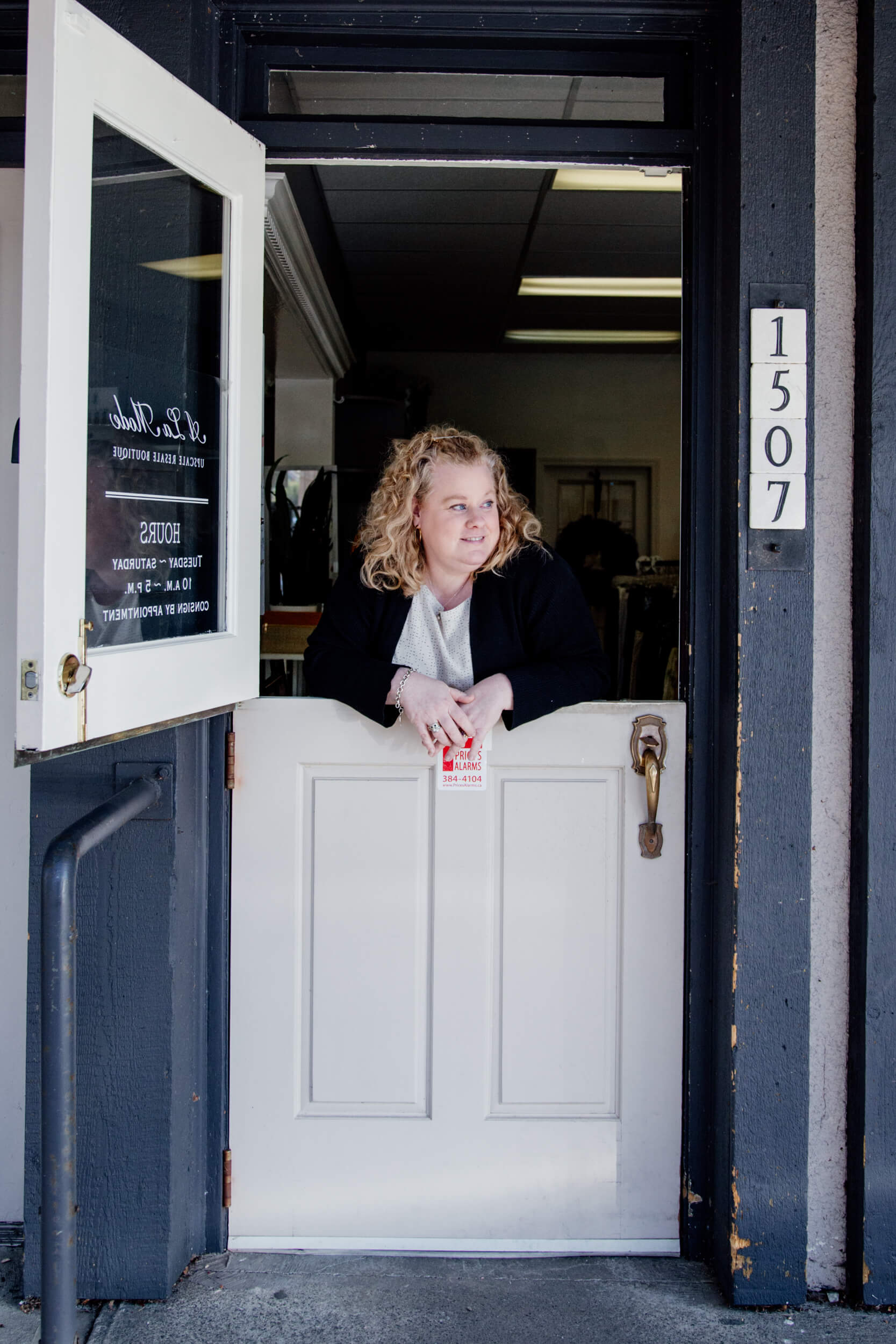 A shopowner leans on the doors at the front of her store.,