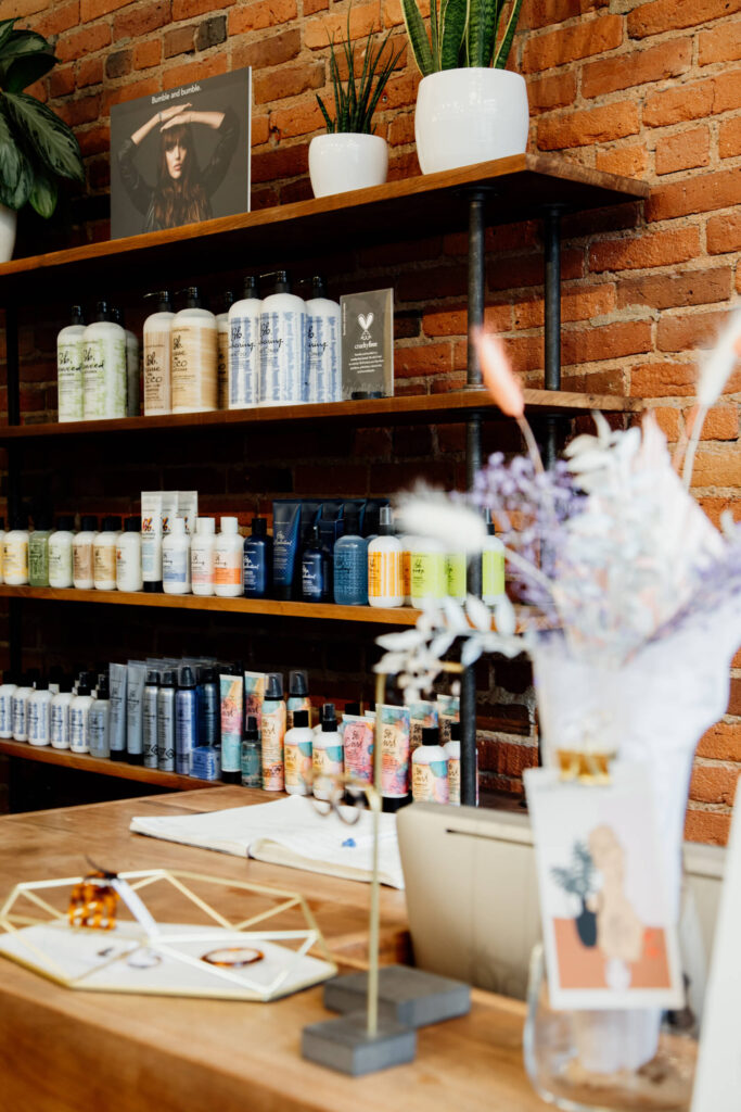 Desk at a hair salon with hair products lining the shelves.