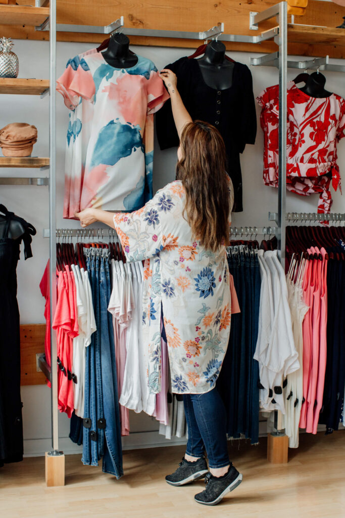 Shopkeeper going through shirts on the racks.