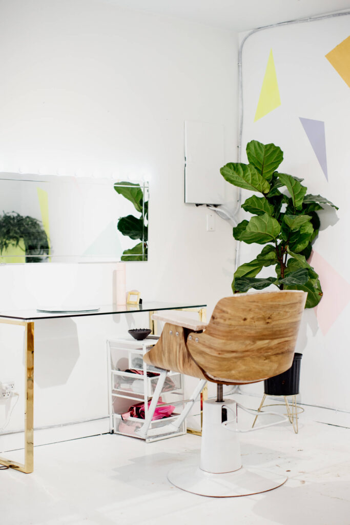 A hair salon chair sits in front of a mirror.