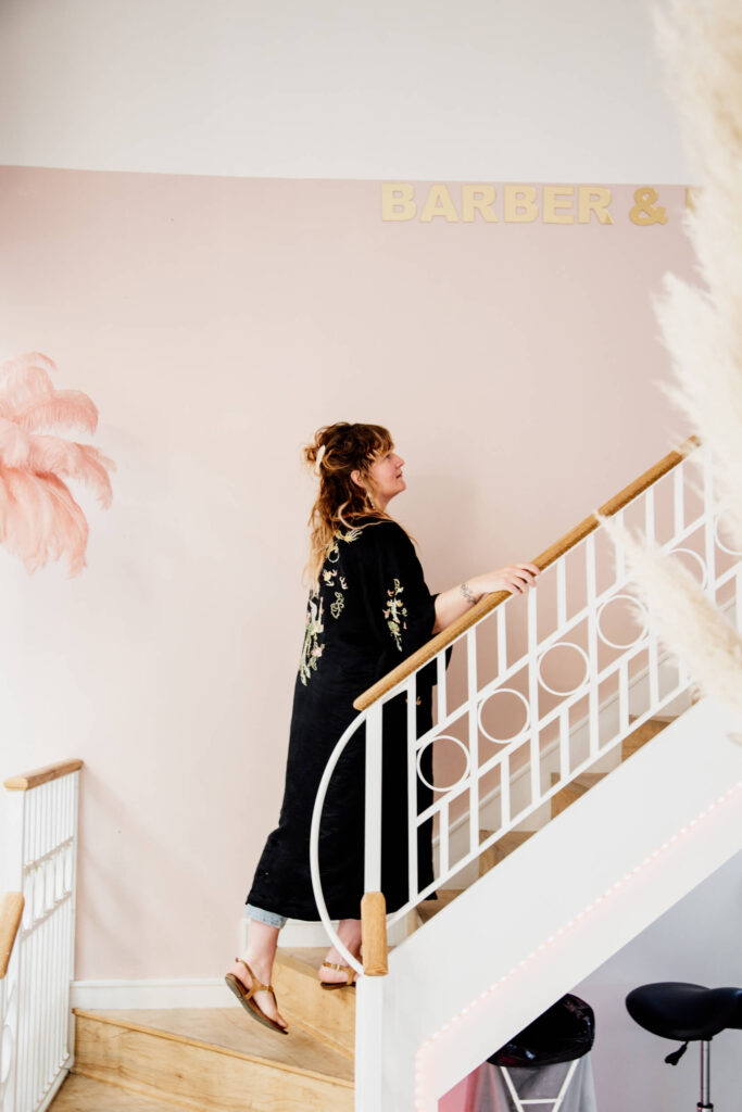 Shop owner going up a staircase in her salon in Victoria, BC.