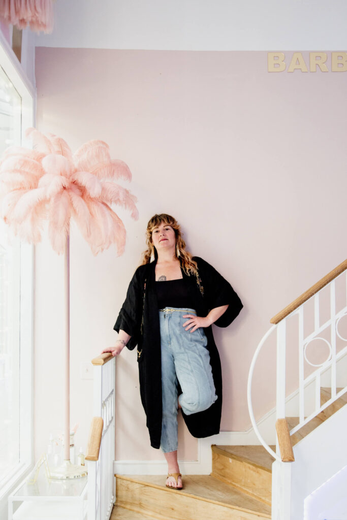 Salon owner standing on the stairs in her shop in Victoria, BC.