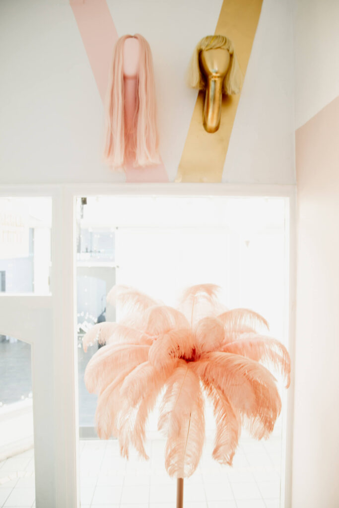 Colourful wigs and a pink palm tree in a hair salon in Victoria, BC.