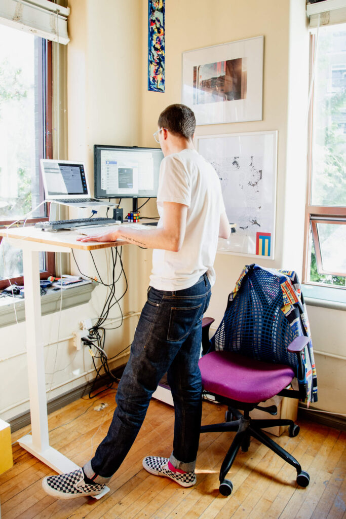 Man working on a stand up desk with front of a laptop.