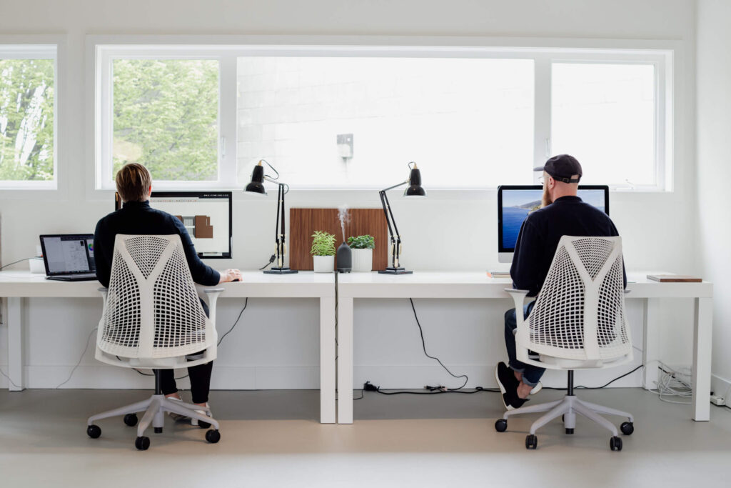 Two designers sit at their desks in an office in Victoria, BC.