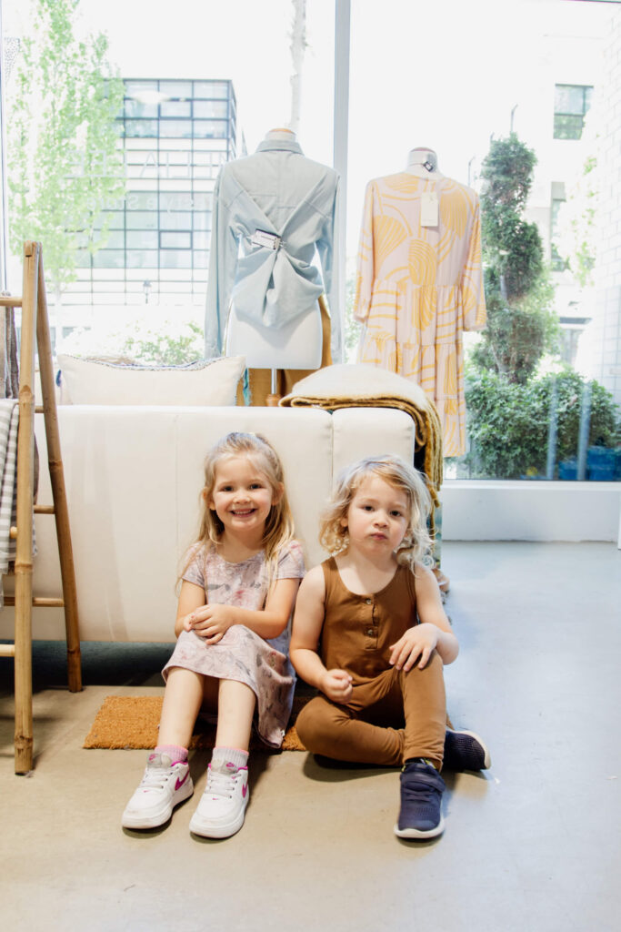 Two young children sit on the floor in a shop in Victoria, BC.