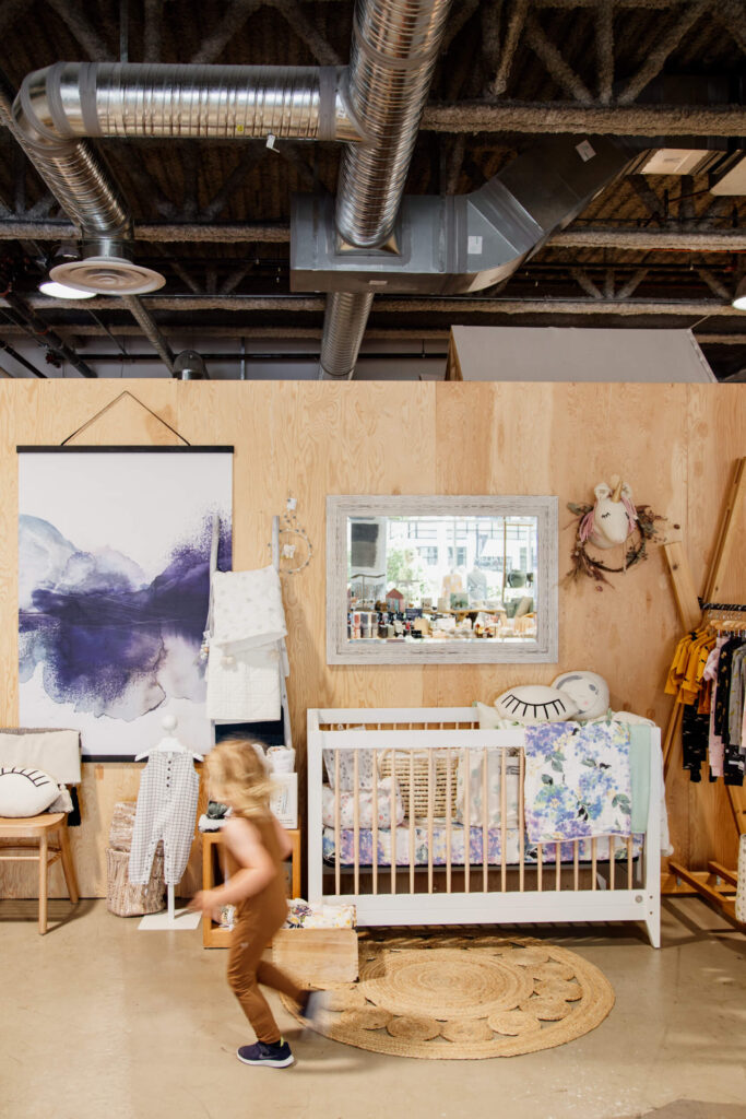 A small child running past a crib in a shop in Victoria, BC.