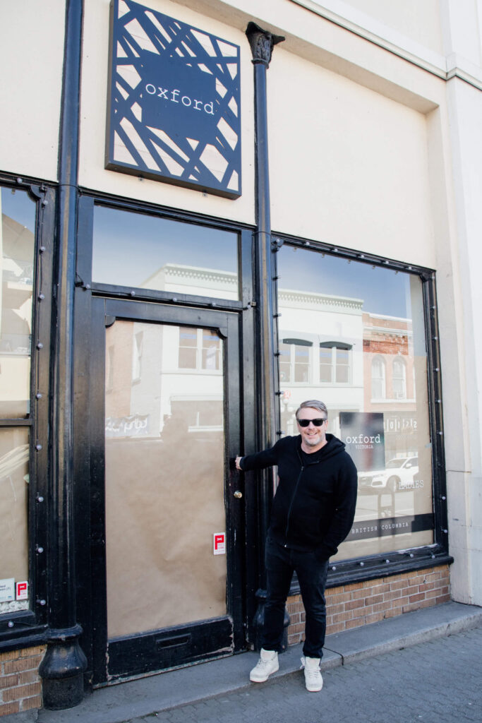 A shop owner outside his shop with papered up windows during Covid.