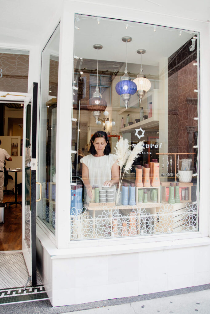 A woman arranging products in a shop window.