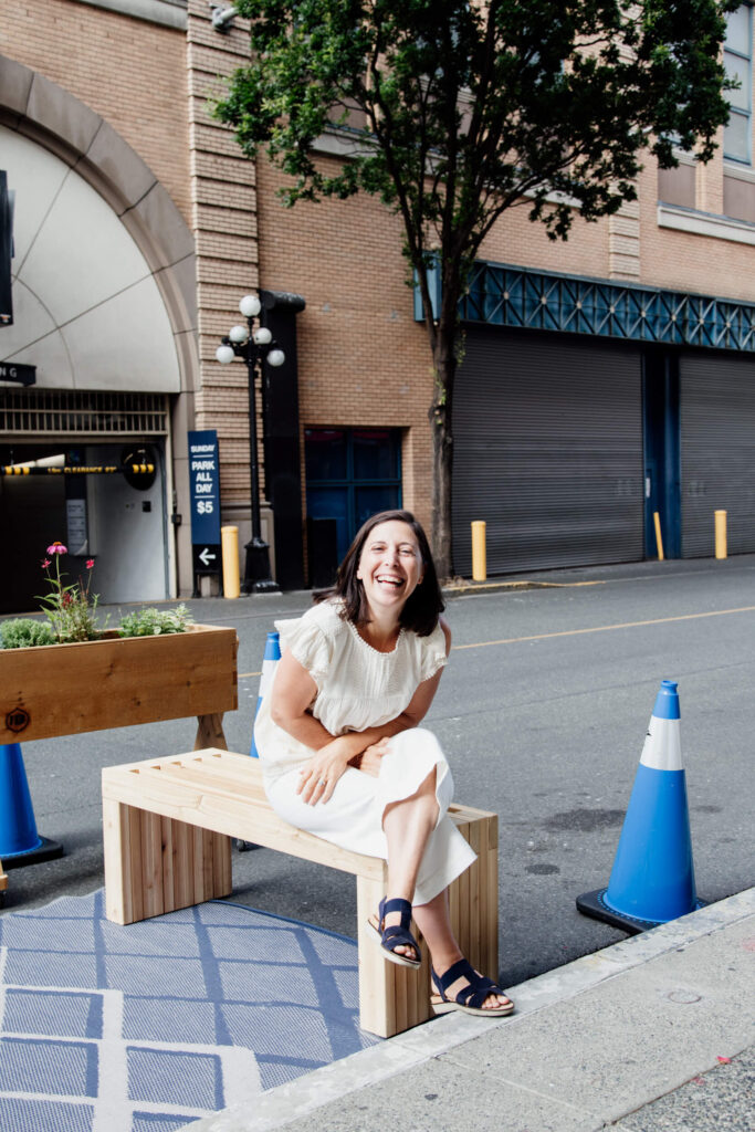 A woman sits on a bench and laughs.