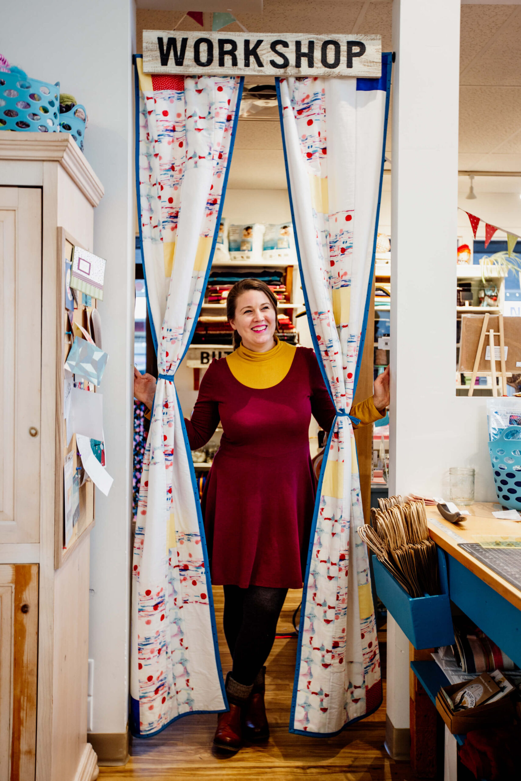 A woman stands and smiles in her sewing shop called The Makehouse in Victoria, BC.