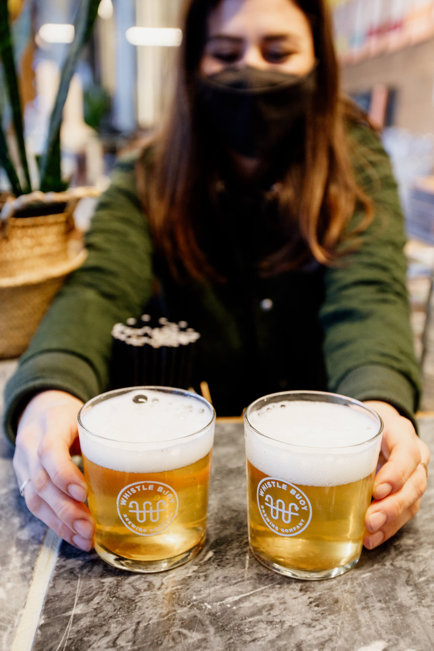 Nina, co-owner of Whistle Buoy Brewing in Victoria, BC, serves up two glasses of beer.