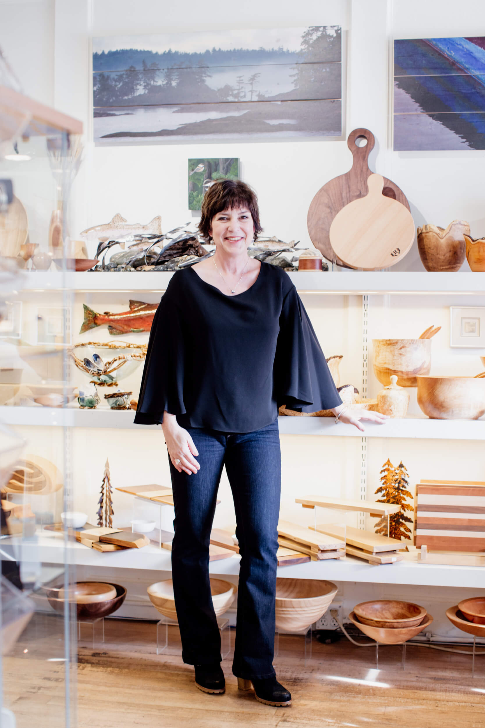 A woman stands in front of her wares in an art shop.