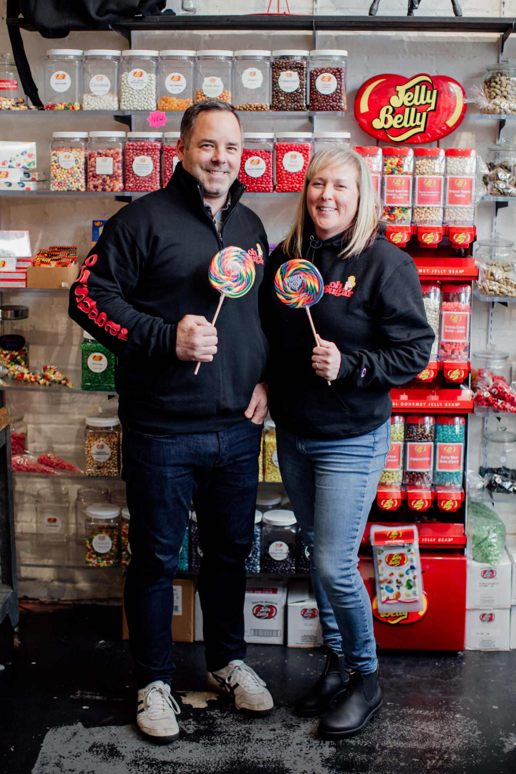 A couple stands in front of their candy shelf.