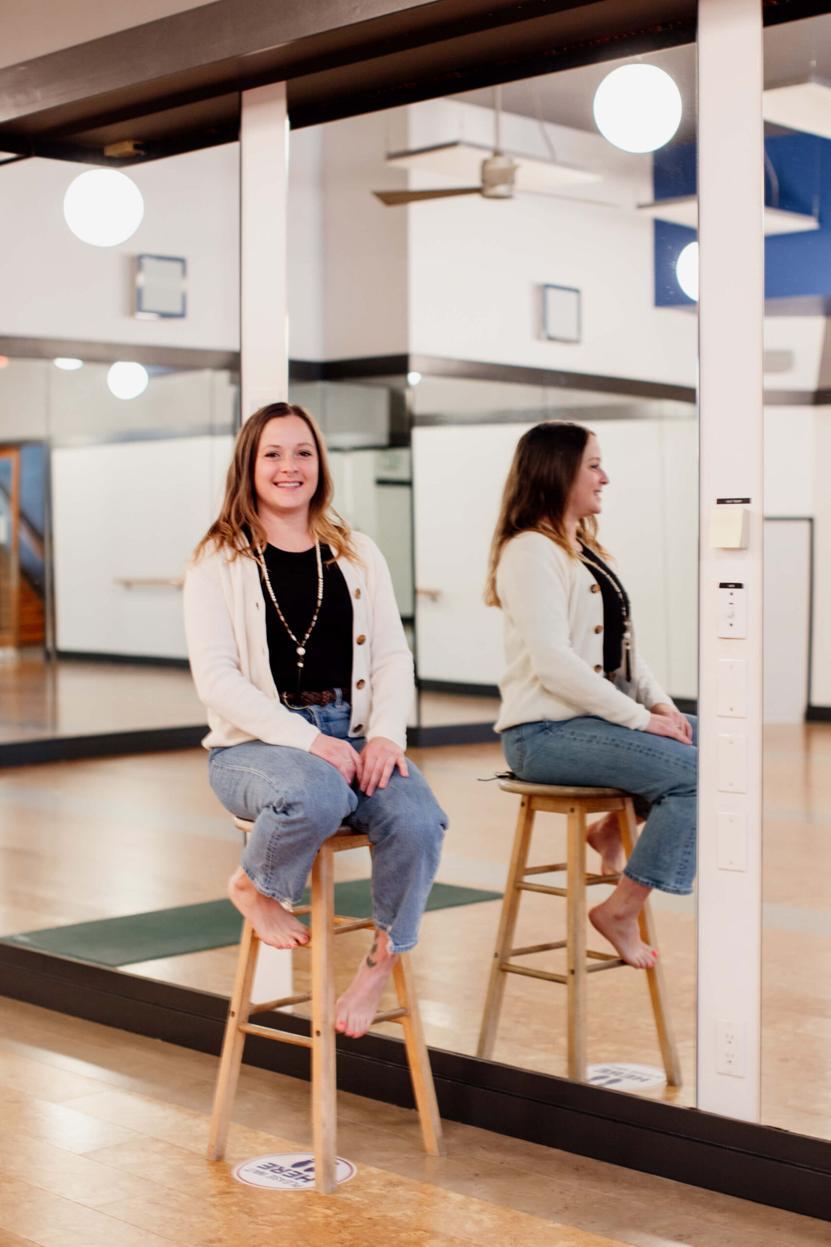 A woman sits on a stool in her yoga studio